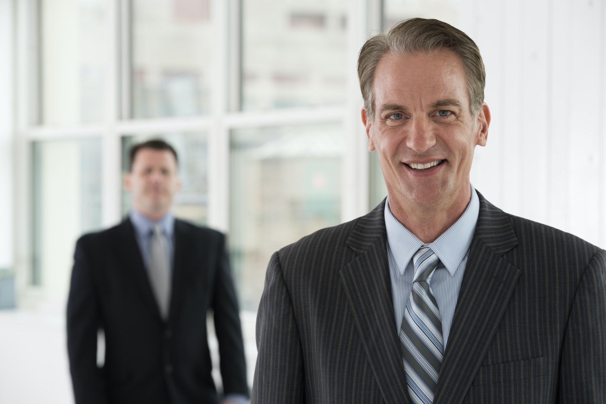 A business environment, a light airy city office. Business people. Two men in suits.